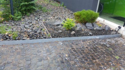 Basalt Kopfsteinpflster Einfahrt im Steingarten mit Nadelkiefer Beet.